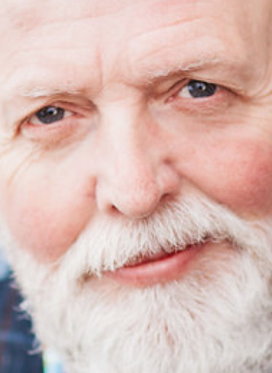 A close-up of an older man with a white beard and blue eyes, smiling gently after a Belong to Yourself Meditation and Healing Retreat. The image features the text 